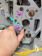 Tensioning the main belt—while pulling it to the left, the 2 screws are tightened.
